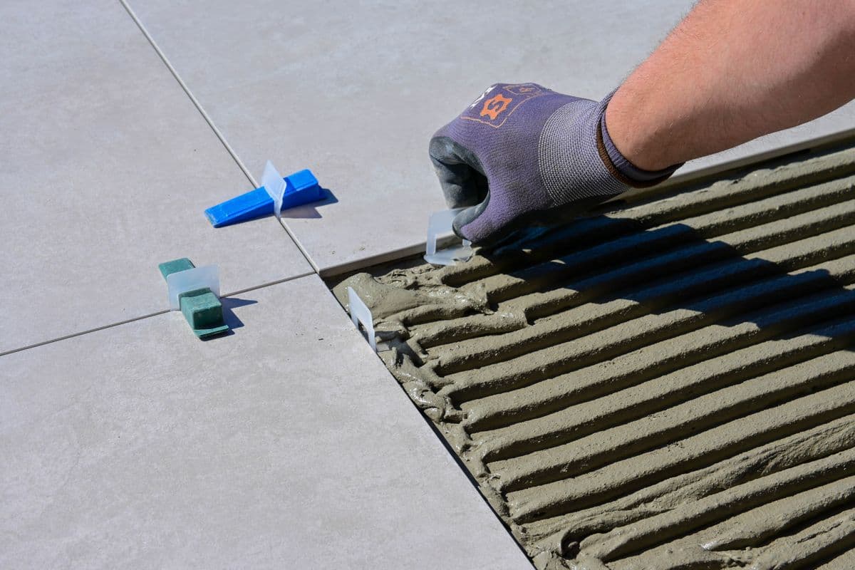 Tile adhesive combed with a notched trowel while large-format tiles are levelled